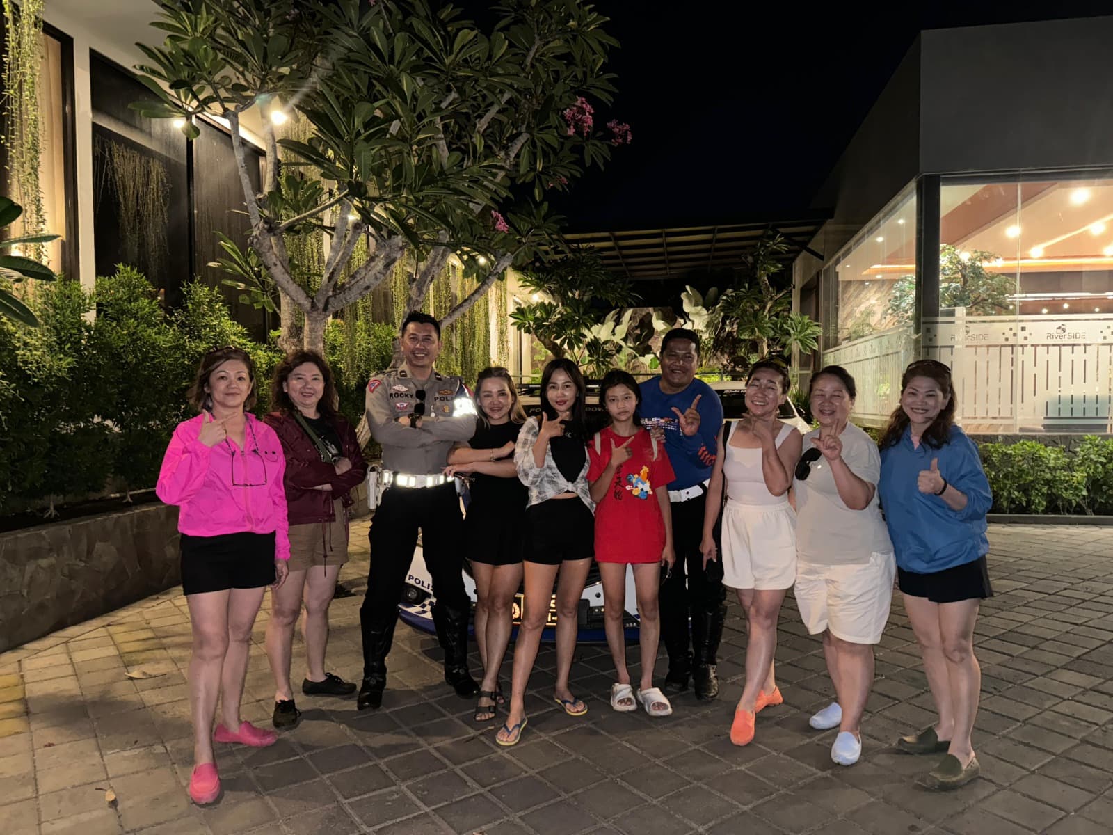 Group of JVTO travelers posing with a traffic police officer in the hotel courtyard at night after an escorted transfer