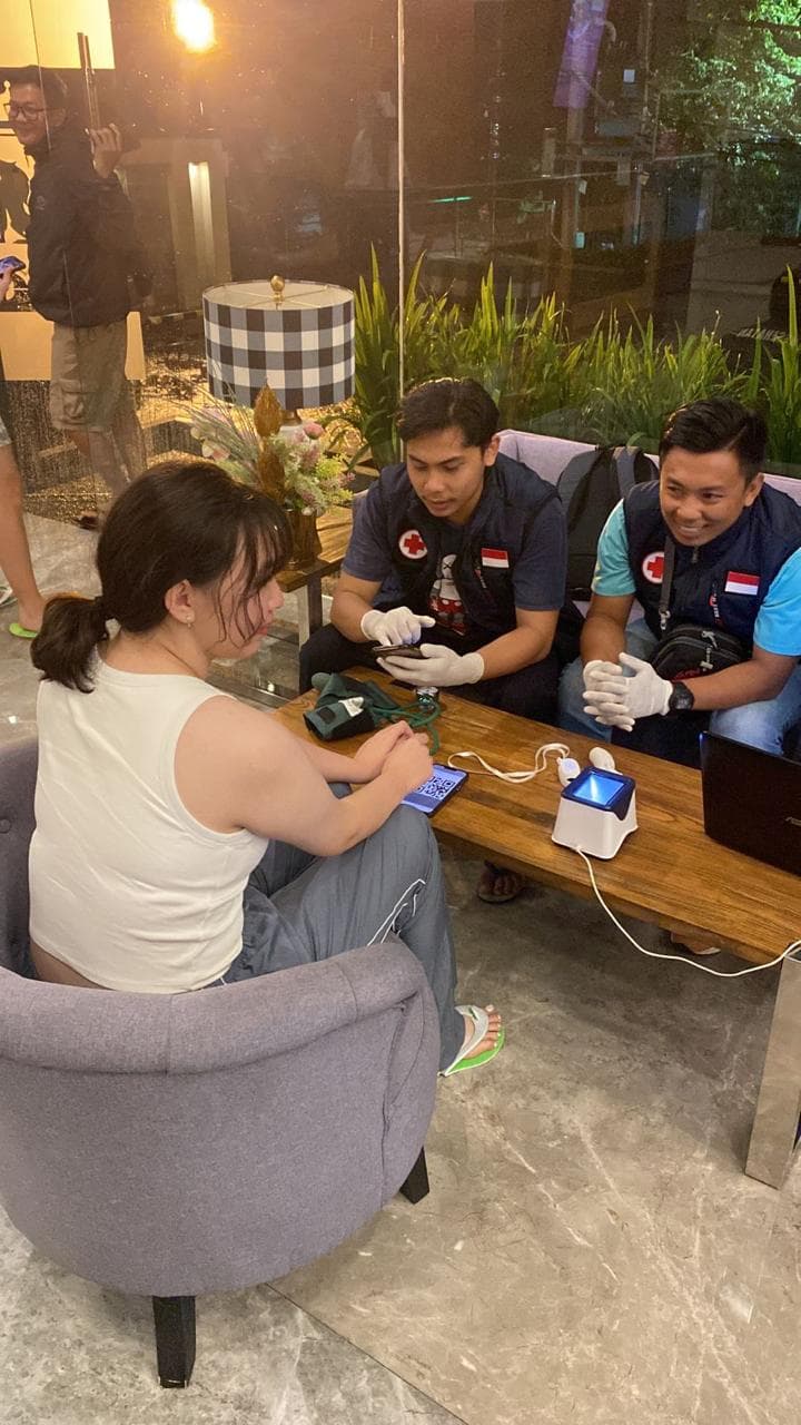 Medical staff measure vitals for adult traveler at a hotel table